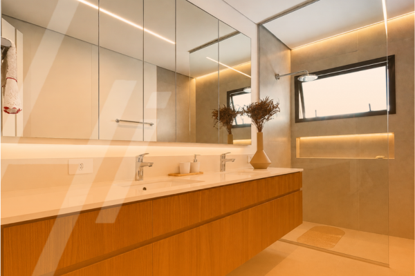 Banheiro planejado com bancada livre, marcenaria amadeirada e espelho amplo